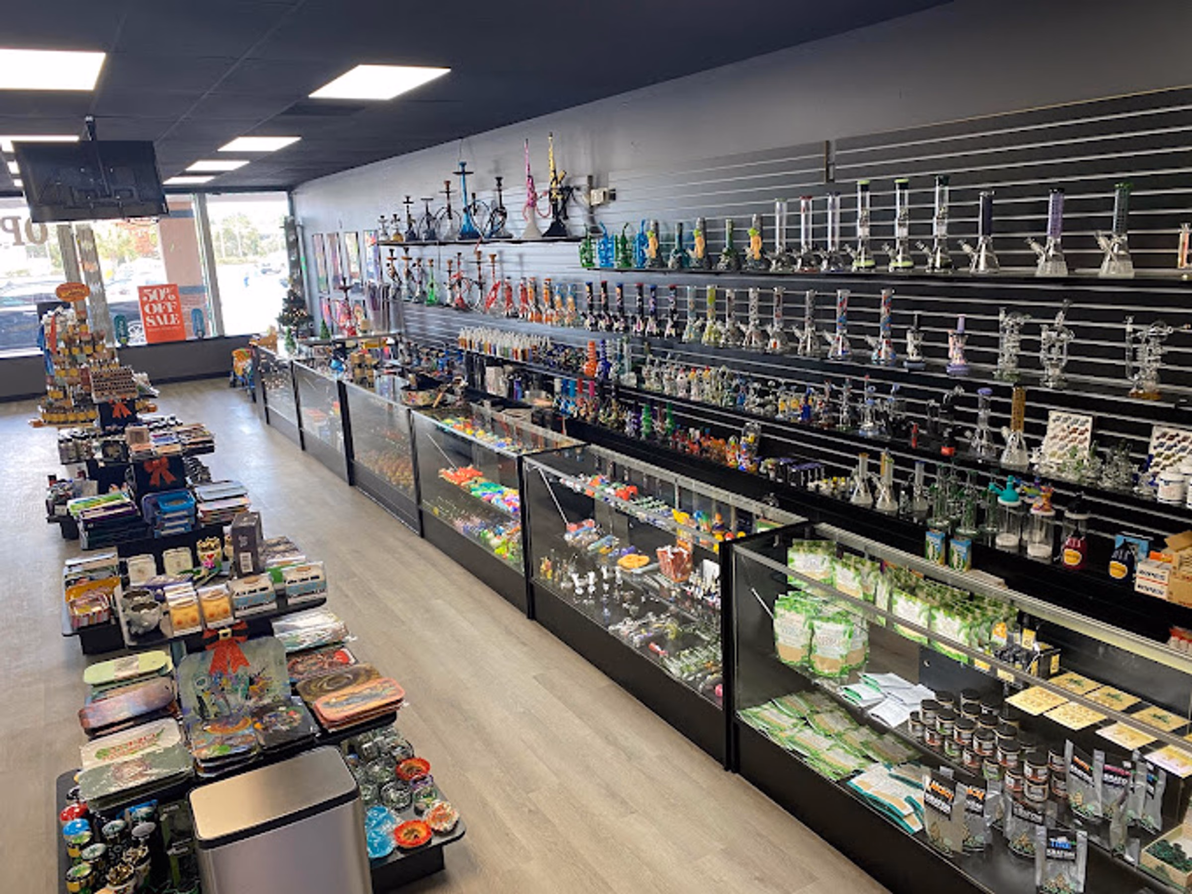 Glass pipe and water pipe wall at Metro Smoke Shop in Mount Dora, with hookahs above and display cases down the aisle